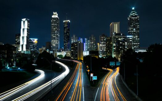 Dramatic city skyline at night with highway light trails representing autonomous vehicle fleets and urban transformation