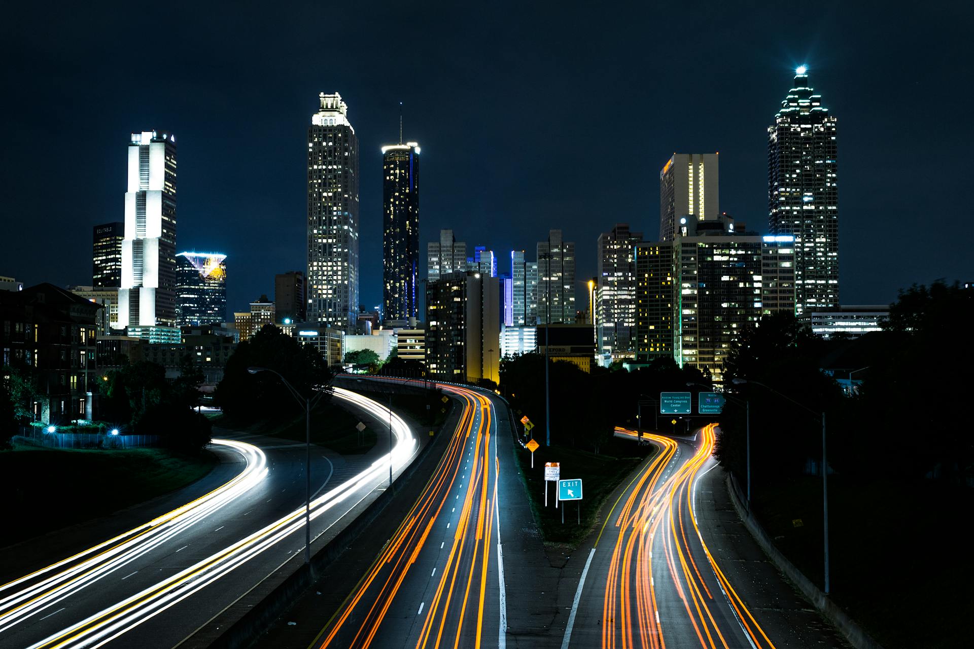 Dramatic city skyline at night with highway light trails representing autonomous vehicle fleets and urban transformation